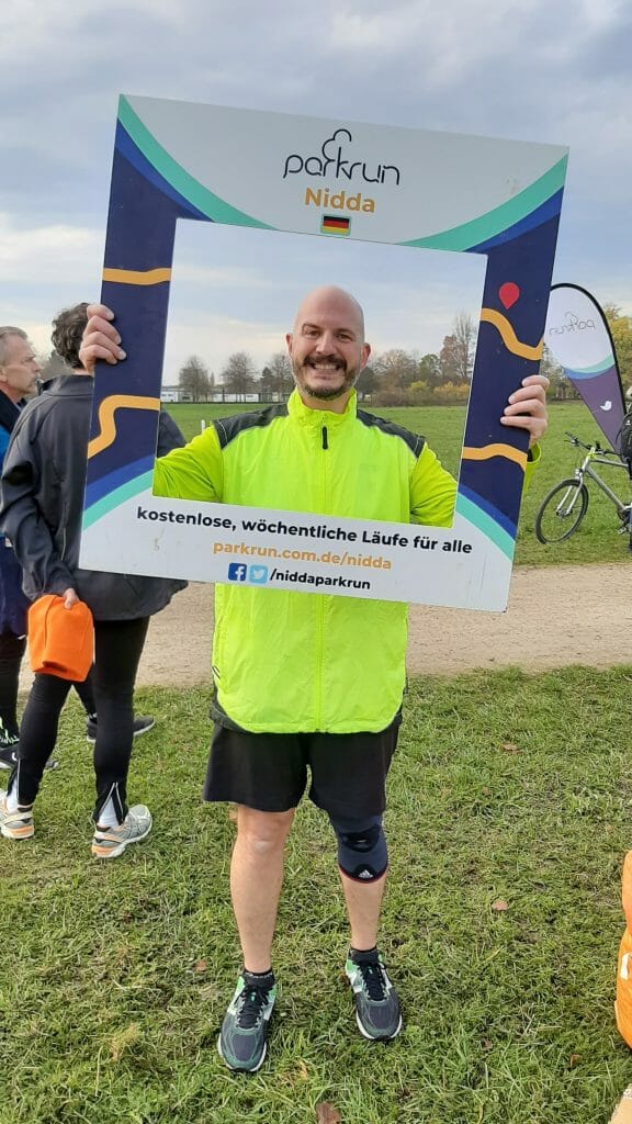 Adem holding up a photoframe from Nidda Parkrun